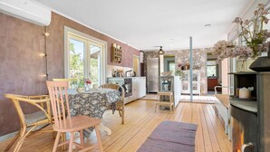 Une cuisine spacieuse avec un plancher en bois, un coin repas avec des chaises en osier et une cheminée.