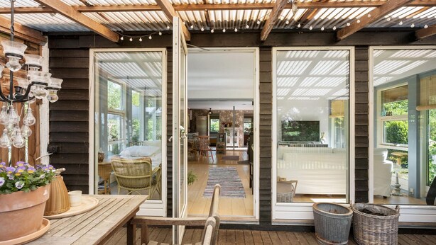Une terrasse en bois avec une table et des chaises, un panier en osier et une plante en pot.
