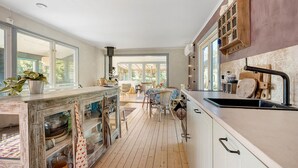 Une cuisine avec un plancher en bois, un îlot central et une vue sur l’espace repas.