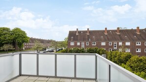 Un balcone con vista libera su una zona residenziale, con case e auto parcheggiate.
