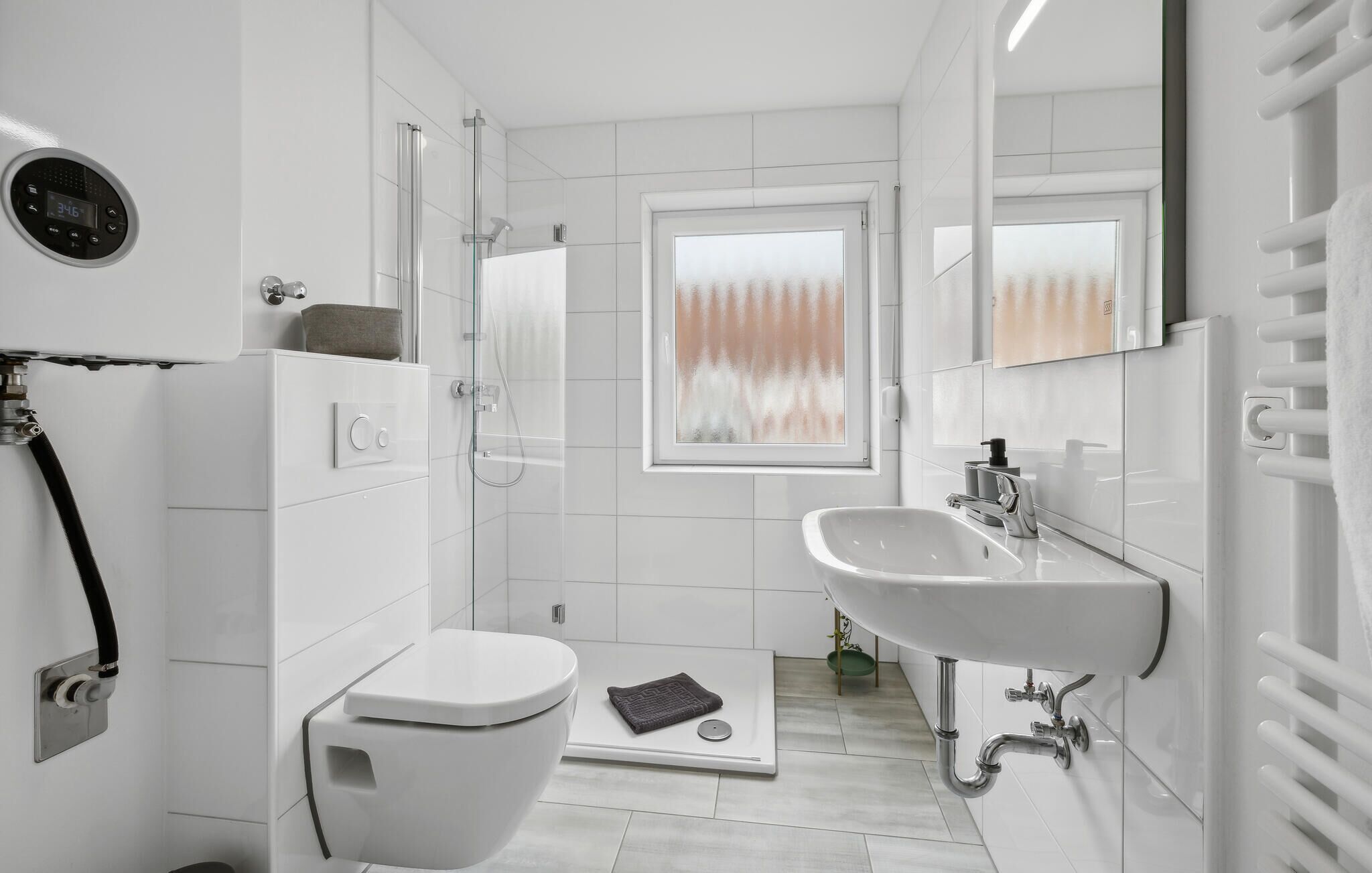 A modern bathroom with a toilet, shower, and sink.