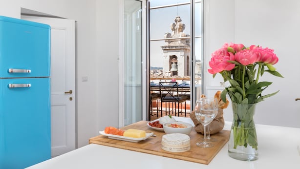 A dining area with a table set for a meal, a vase of flowers, and a view of a bell tower through a glass door. - Penthouse with Terrace, Pantheon and 360° City views!! Walk to all attractions (Roma)
