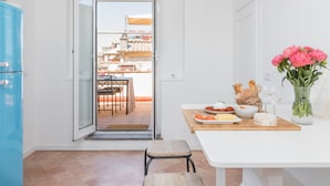 A modern kitchen with a dining area, a blue refrigerator, and a view of the city through the open door. - Penthouse with Terrace, Pantheon and 360° City views!! Walk to all attractions (Roma)