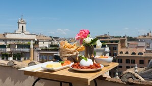 A table with food and flowers on a terrace overlooking a cityscape with historic buildings. - Penthouse with Terrace, Pantheon and 360° City views!! Walk to all attractions (Roma)