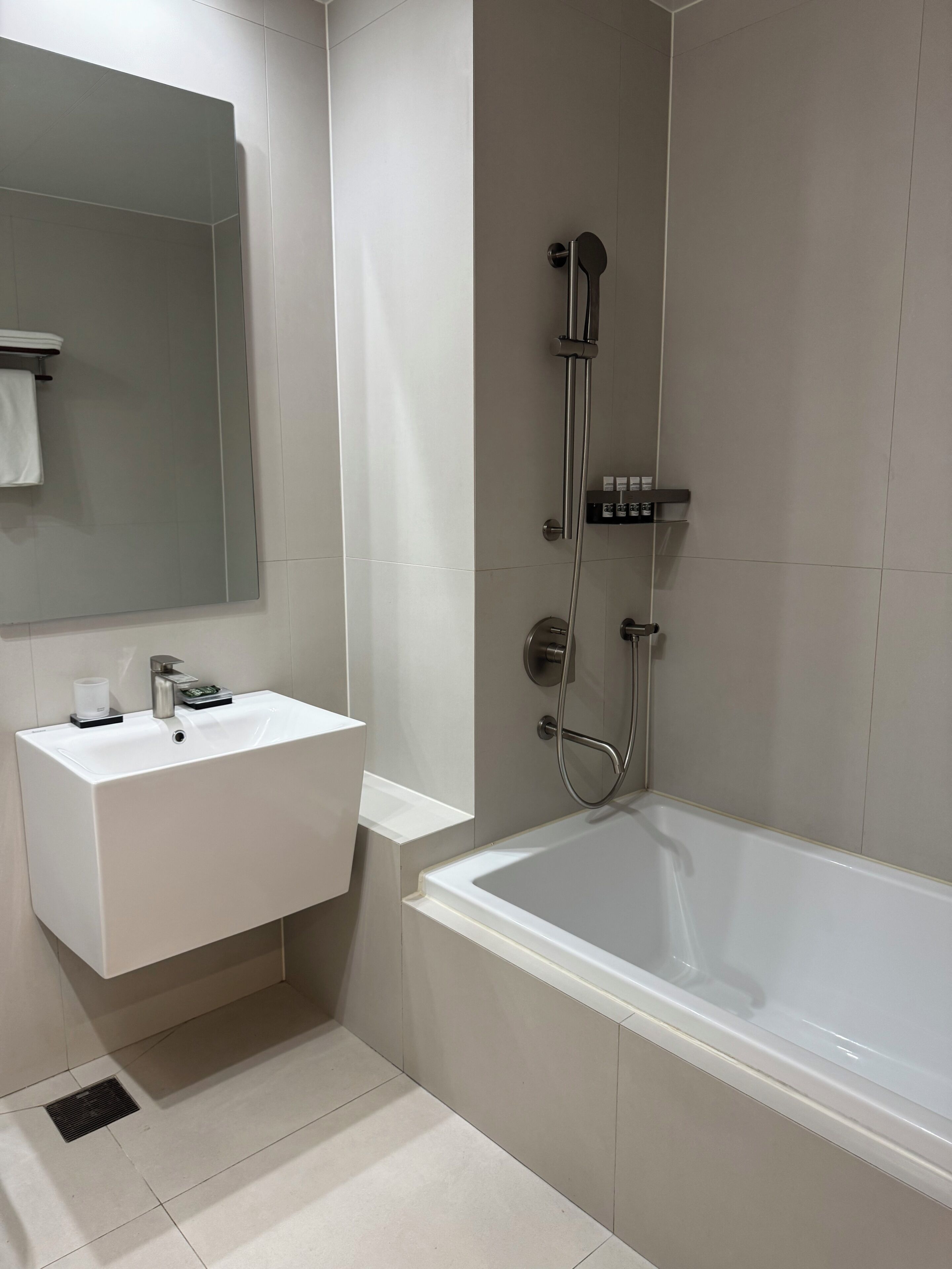 A modern bathroom with a white sink, mirror, and bathtub.