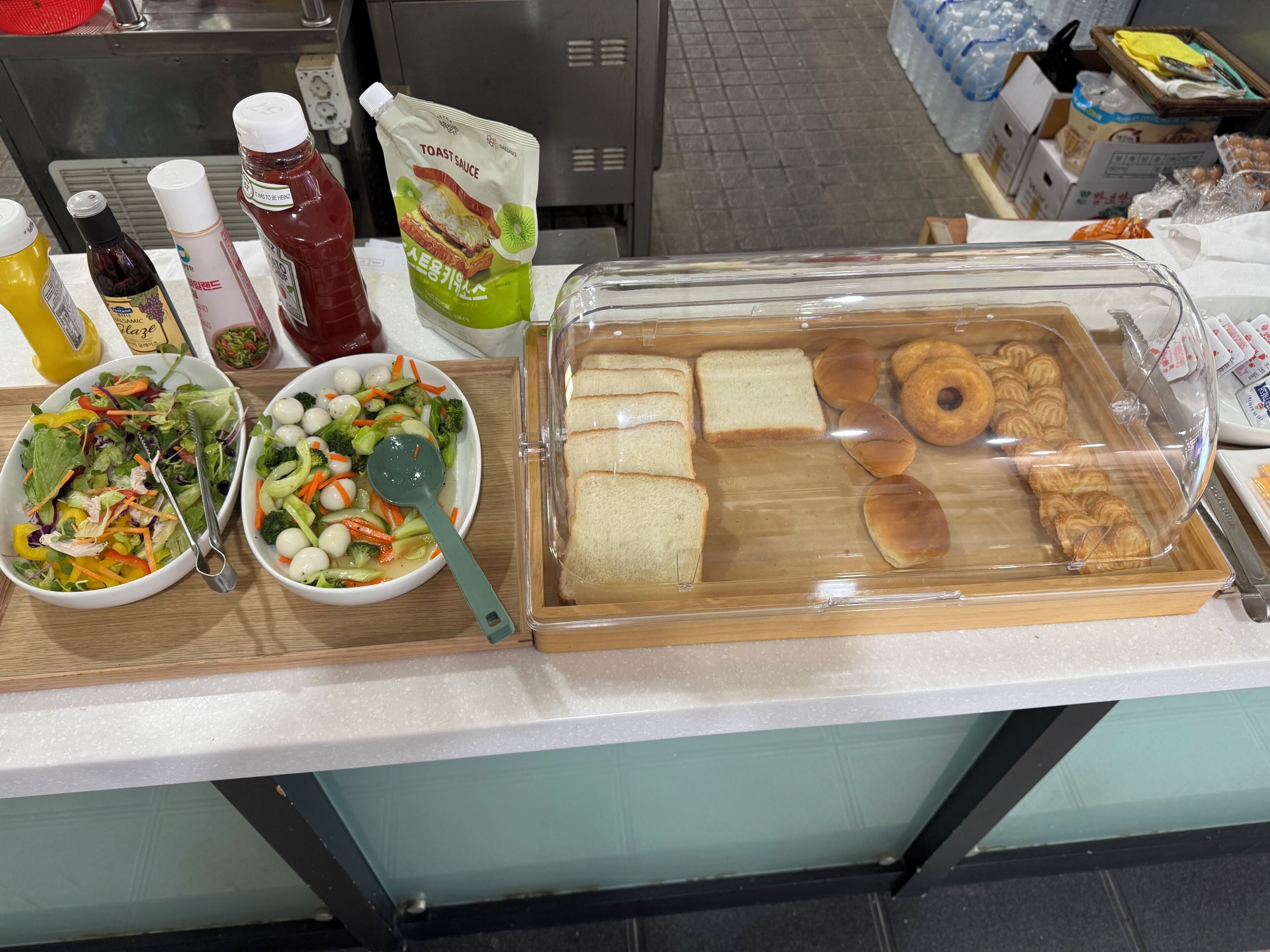 A buffet table with various food items, including bread, pastries, and a salad.