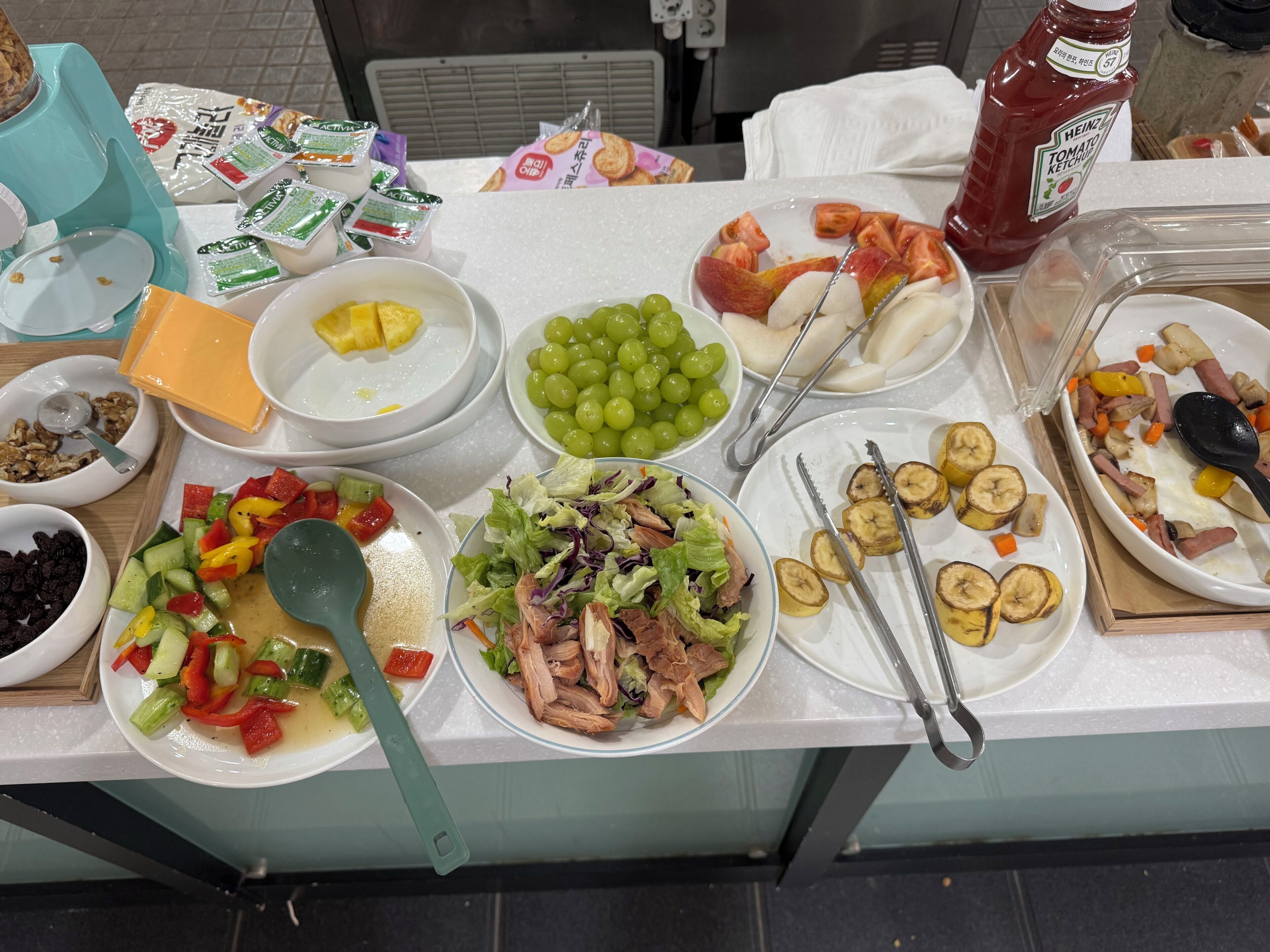 A buffet table with various food items including fruits, vegetables, salads, and condiments.