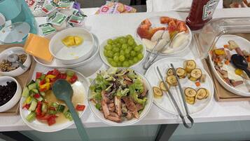 A buffet table with various food items including fruits, vegetables, salads, and condiments.