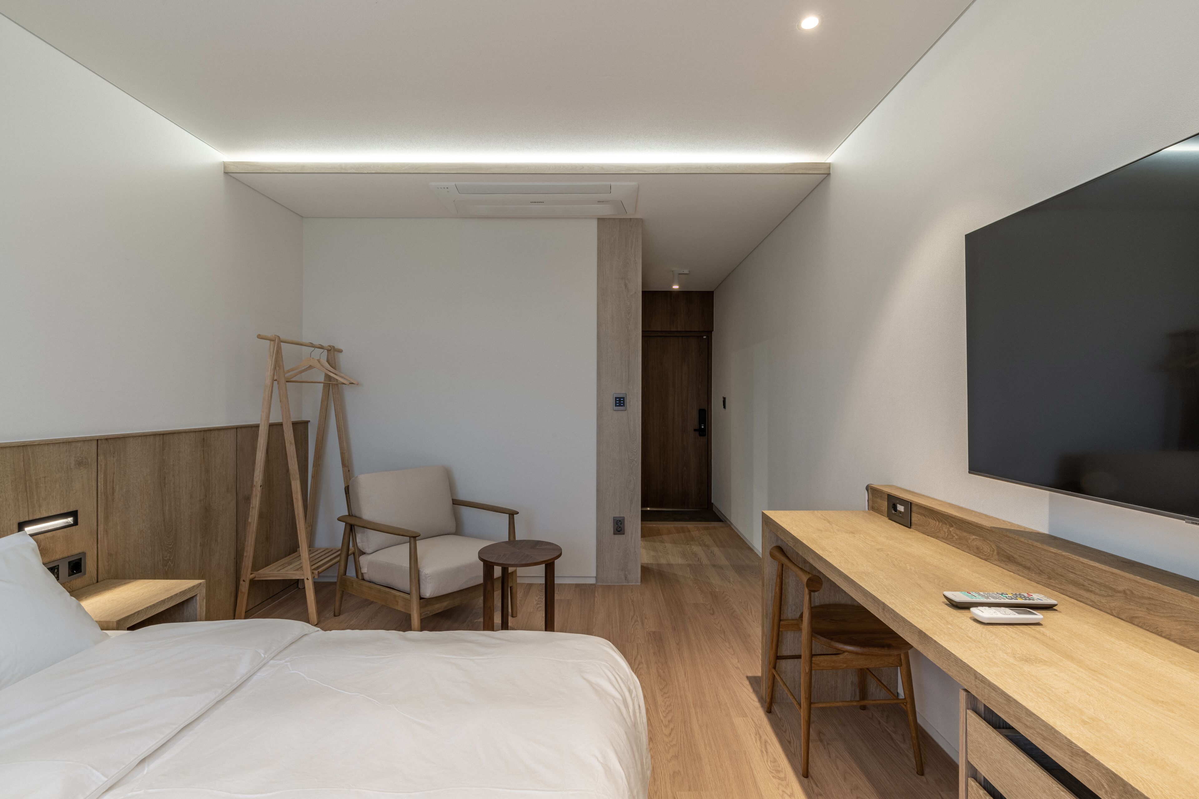 Una habitación de hotel con una cama, un escritorio, una silla, un televisor y un armario.