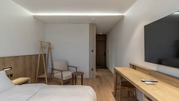 Una habitación de hotel con una cama, un escritorio, una silla, un televisor y un armario.