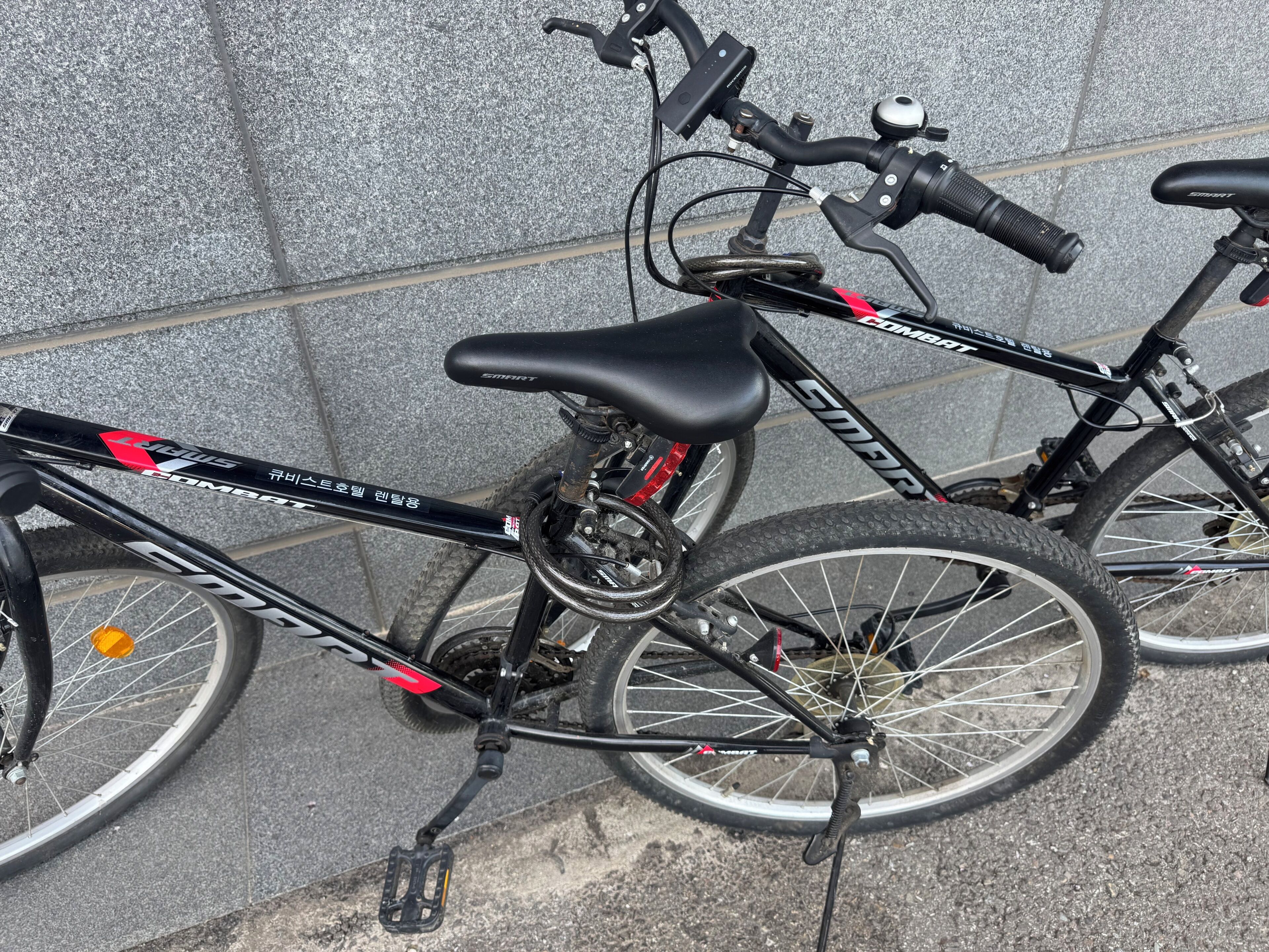 Ein Fahrrad mit schwarzem Rahmen und roten Akzenten, an einer strukturierten Wand geparkt.