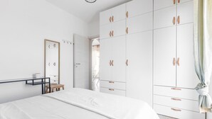Ein Schlafzimmer mit Bett, Kleiderschrank, Spiegel und einem kleinen Tisch.