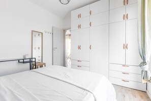 A bedroom with a bed, a wardrobe, a mirror, and a small table.
