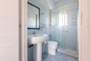A bathroom with a sink, toilet, and glass-enclosed shower.