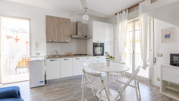 Eine moderne Küche mit weißen Schränken, einem Gasherd, einem Backofen und einem Deckenventilator.