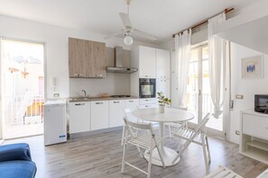 Una cocina moderna con armarios blancos, estufa a gas, horno y ventilador de techo.