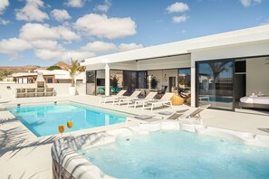 Un hotel moderno con piscina, sillones de descanso y bañera de hidromasaje.