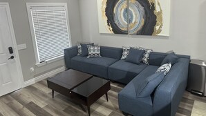 Una sala de estar moderna con un sofá modular, una mesa de centro y un cuadro abstracto grande en la pared.
