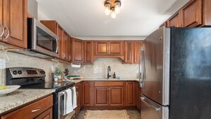 A kitchen with wooden cabinets, stainless steel appliances, granite countertops, and a backsplash. - Barefoot Beach on Pigeon Lake  (Bobcaygeon)