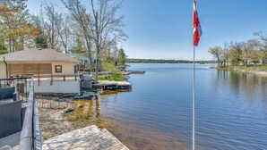 A lakeside property with a dock, a flag, and a building with a sloped roof. - Barefoot Beach on Pigeon Lake  (Bobcaygeon)