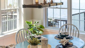A dining area with a table set for six, a hanging light fixture, and a view of the water outside. - Barefoot Beach on Pigeon Lake  (Bobcaygeon)