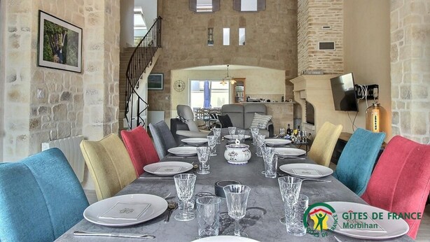 A dining area with a stone wall, a staircase, and a view of the kitchen. - Ker Rosy - Saint Gildas DE Rhuys (SAINT GILDAS DE RHUYS)
