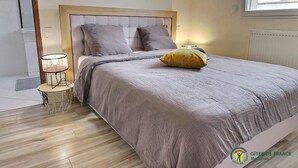 A bedroom with a bed, a bedside lamp, and a window. - Ker Rosy - Saint Gildas DE Rhuys (SAINT GILDAS DE RHUYS)