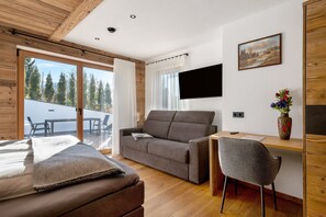 Une chambre moderne avec un canapé, un bureau, une chaise, un téléviseur et un tableau au mur.