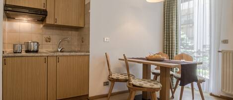 Una cocina con armarios de madera, un lavamanos y un comedor con dos sillas y una mesa.