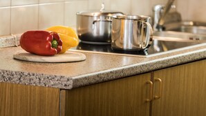 A kitchen counter with a cutting board, a red bell pepper, a yellow bell pepper, a stainless steel pot, and a stainless steel mug.