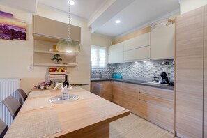 A modern kitchen with wooden cabinets, a dining table with placemats, and a hanging light fixture.