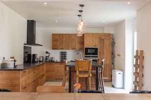 Une cuisine moderne avec des meubles en bois, un îlot central et un luminaire suspendu.