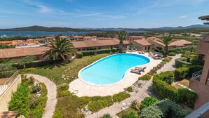 A swimming pool surrounded by greenery, with a view of a lake and mountains in the background. - Apartment 'Il Fiordo 28' with Sea View, Shared Pool and Air Conditioning (Santa Teresa Gallura)