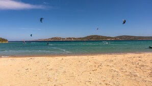 En strand med klare himmel, roligt vand og fjerne bakker.