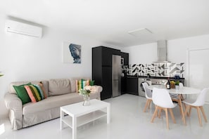Een moderne woonruimte met een bank, salontafel, eethoek, keuken en kunstwerken.