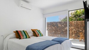 Un dormitorio con dos camas, una pared de piedra en el exterior y vista a zonas verdes.