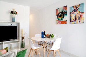 A modern living room with a flat-screen TV, white furniture, and two paintings on the wall. - Holiday Home 'Titán' with Sea Views, Wi-Fi, and Air Conditioning (La Santa)