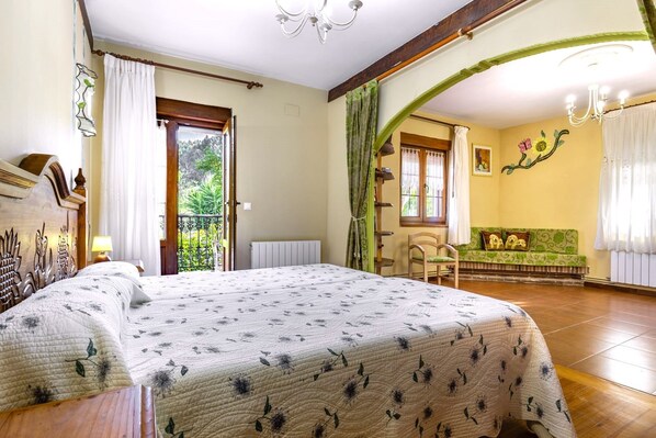 A bedroom with a bed, a window, a balcony, and a green sofa.