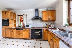 A kitchen with wooden cabinets, a microwave, a dishwasher, and a sink. - Holiday Home 'Casa Rural La Praderia' with Mountain Views, Private Terrace and Wi-Fi (Vidular)
