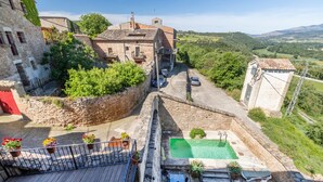 Un patio con piscina, asientos exteriores y un edificio de piedra con puerta roja.