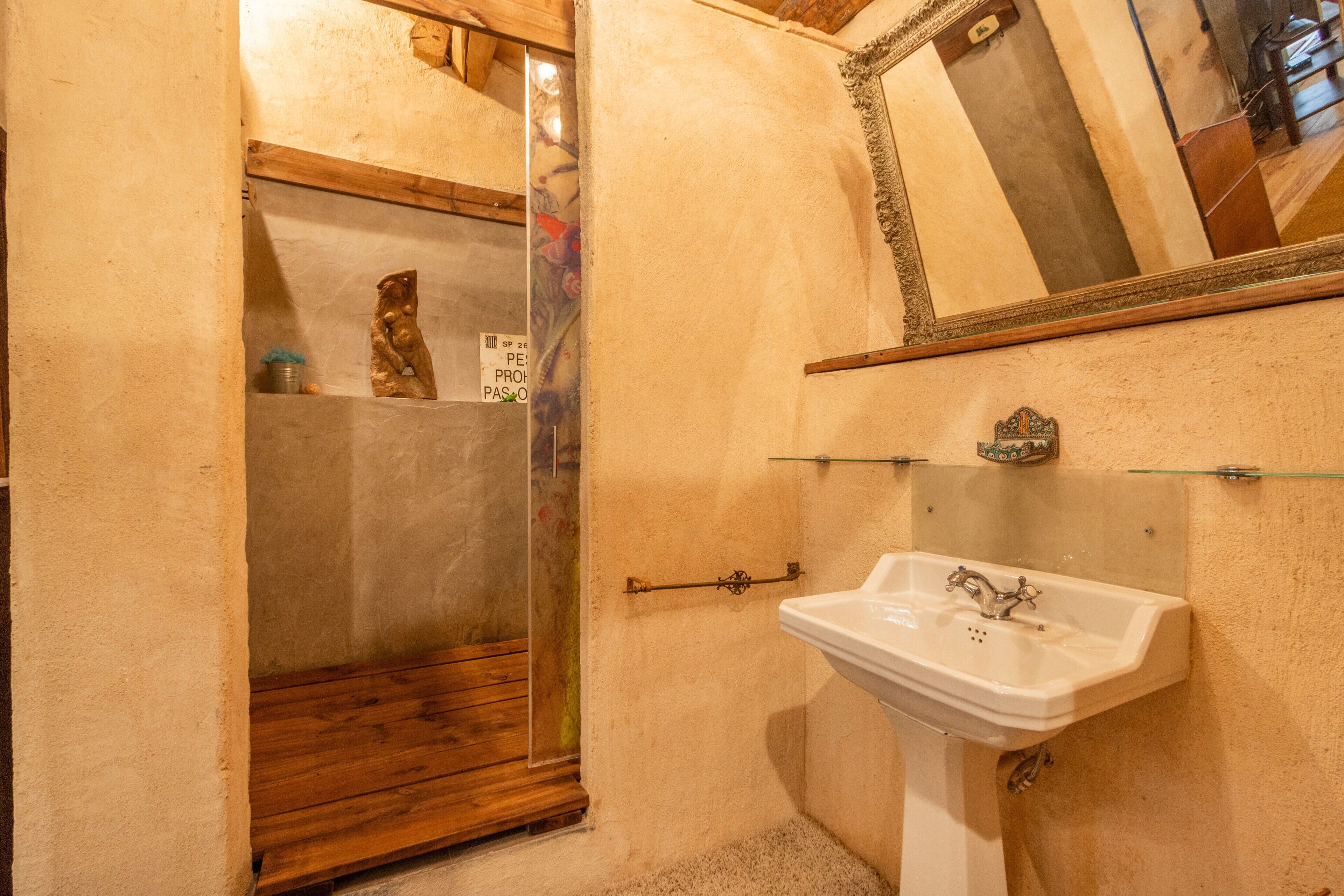 Un baño con cabina de ducha de madera, un lavabo blanco y un espejo en la pared.