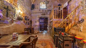 Interior de paredes de piedra con una mesa de madera, sillas, una escalera y un sistema de sonido.