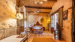 Un dormitorio con techo de madera, una cama, una mesita de noche, una lámpara y una ventana.