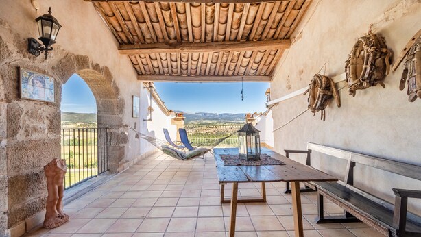 Una terraza con una mesa, bancos, una hamaca y vistas al campo.