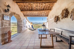 Une terrasse avec une table, des bancs, un hamac et une vue sur la campagne.