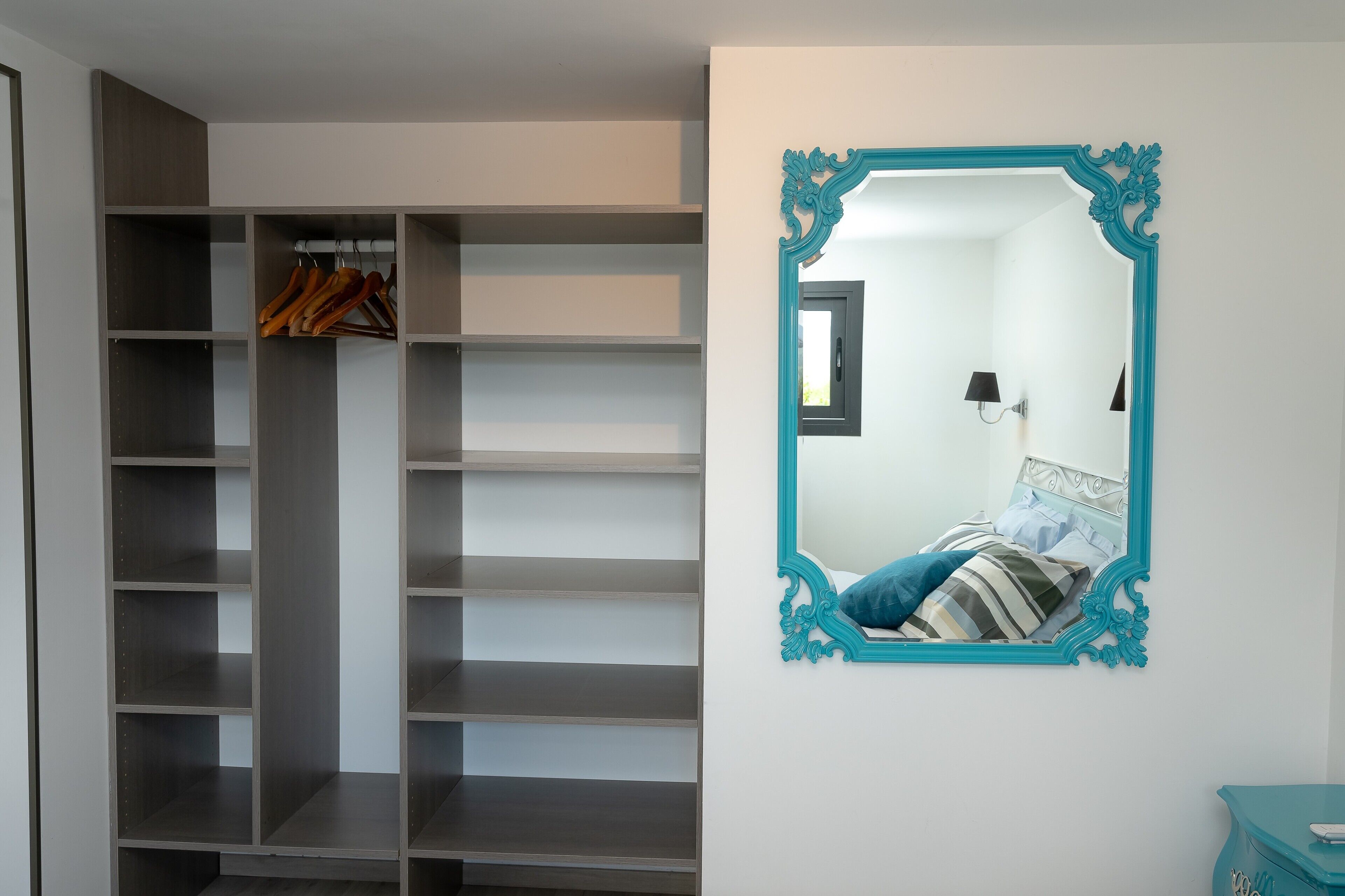 A bedroom with a bed, a mirror, and a wardrobe.