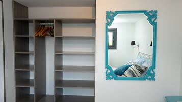 A bedroom with a bed, a mirror, and a wardrobe.