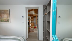 A bedroom with a bed, a chair, a wardrobe, and a door leading to a hallway. - Holiday Home 'Le Balcon Des Bauges' with Mountain View, Shared Pool and Wi-Fi (LA MOTTE-SERVOLEX)