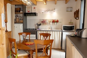 Una cocina con muebles de madera, un refrigerador, un microondas y un lavamanos.