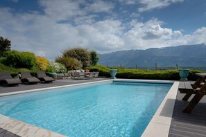 Ein Swimmingpool mit Liegestühlen und Blick auf die Berge.